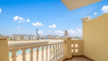 A balcony with a view of a beach and cityscape, including a tall building.