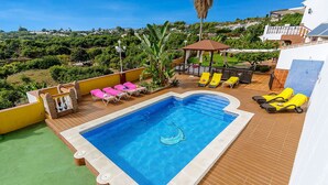 Une piscine dotée de chaises longues, d’une pergola et offrant une vue sur une colline.