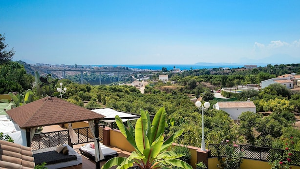 Une villa dotée d’un jardin privé, d  ’un belvédère et offrant une vue sur la mer et le paysage urbain lointain.