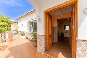 A house with a tiled patio, a wooden door, and a stone wall.
