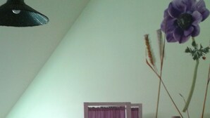 Un dormitorio con dos camas, un armario de madera, una mesita de noche y una lámpara colgante.