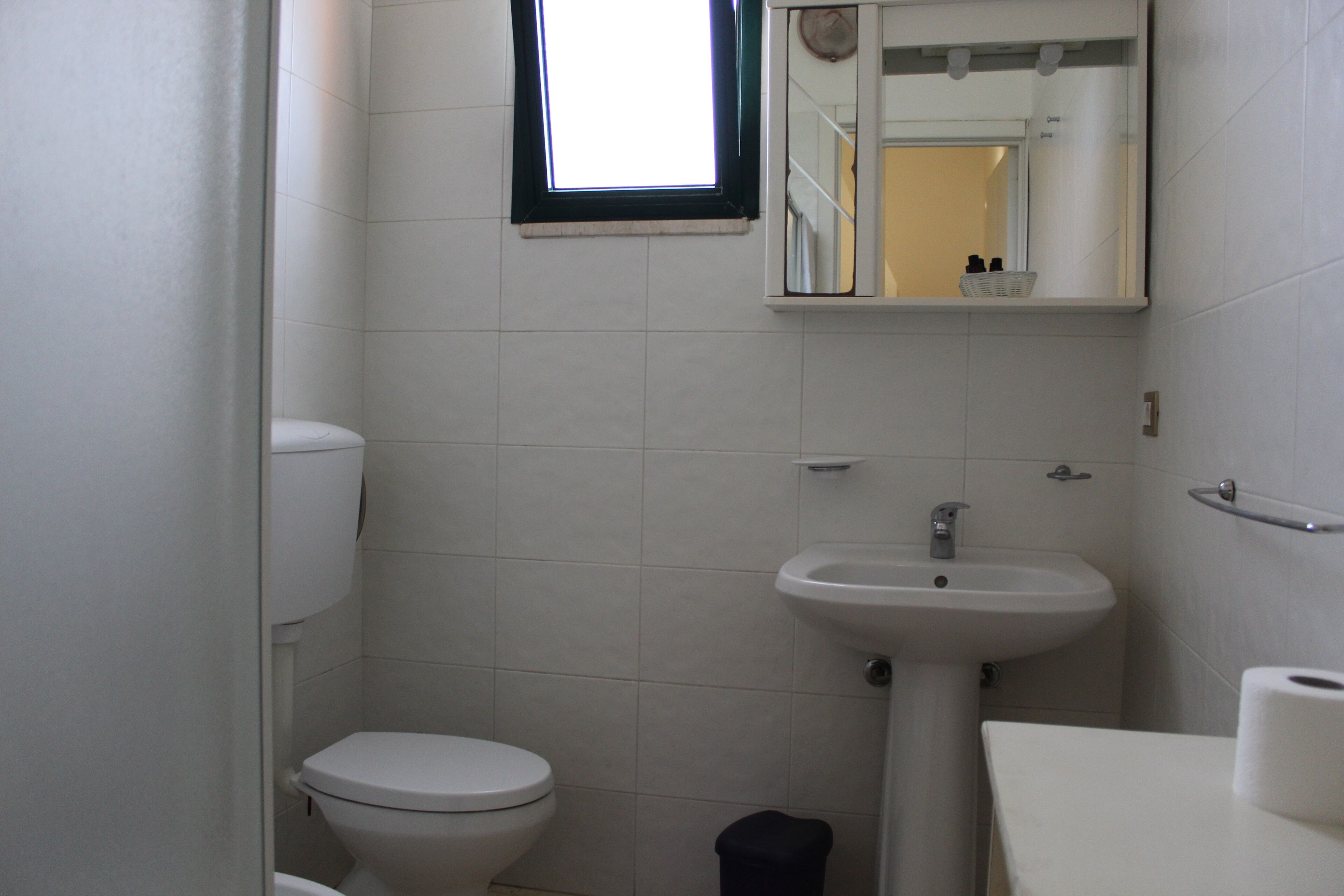 A small, clean bathroom with a toilet, sink, and mirror.