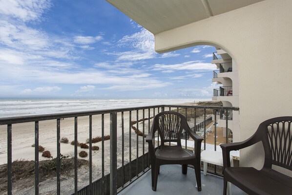 A balcony with a view of the beach and ocean.
