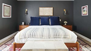 A bedroom with a bed, two bedside tables, a bench, and artwork on the walls. - Eclectic & Stylish Home - Centrally located w/ heated pool, & more! (Phoenix)