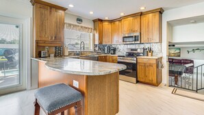 Una cocina con armarios de madera, encimera de granito, electrodomésticos de acero inoxidable y una isla integrada con asientos.