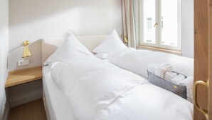 Une chambre d’hôtel avec deux lits, une table de chevet, une lampe et une fenêtre avec des rideaux.