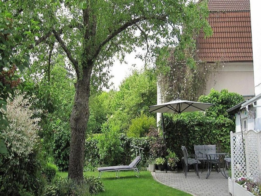 Ein Garten mit Baum, Liegestuhl und Tisch mit Stühlen.