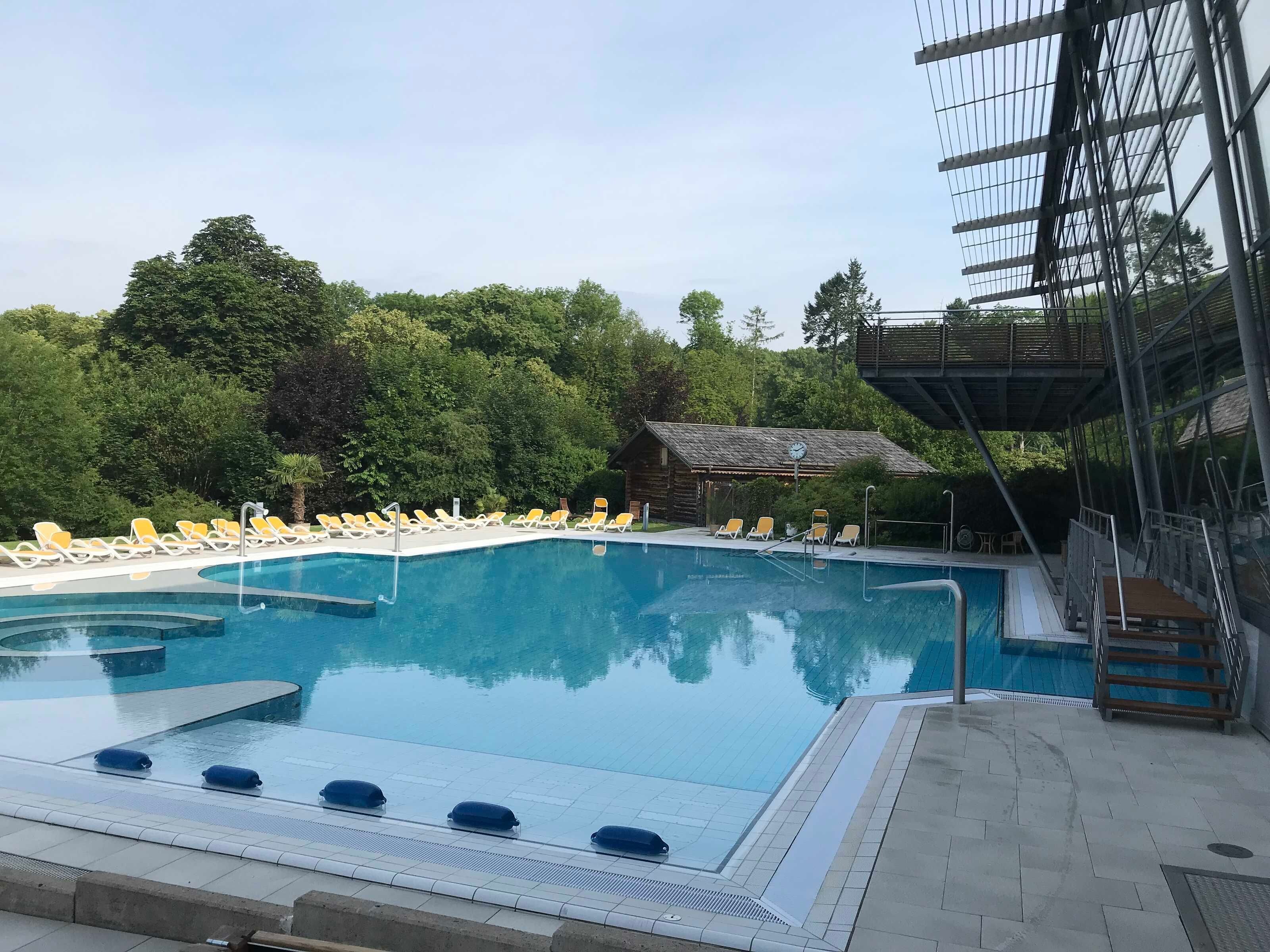 A swimming pool with sun loungers and a covered area.
