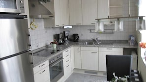 Una cocina equipada con refrigerador, horno, microondas, cafetera y pileta.