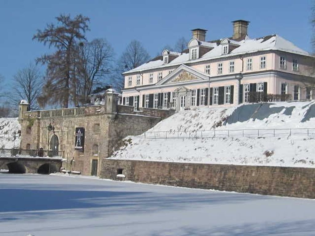 Ein großes, historisches Gebäude mit einer symmetrischen Fassade, einem markanten Eingang und einer schneebedeckten Landschaft.