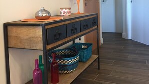 A hallway with a wooden console table, a mirror wall, and a door.