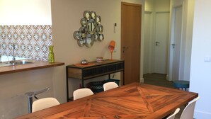 A dining area with a wooden table and white chairs, a decorative mirror wall, and an air conditioning unit.