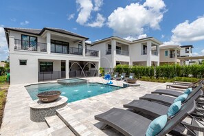 Ein modernes, zweistöckiges Haus mit Schwimmbad, Sitzgelegenheit im Freien und einem gepflegten Garten.