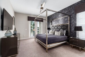 Ein modernes Schlafzimmer mit einem Himmelbett, einer dunkelholz-Kommode, einem Nachttisch mit Lampe und einer Wand mit Marmoroptik.