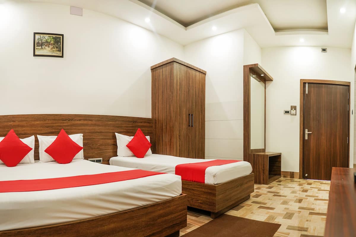 A hotel room with two beds, a wardrobe, a mirror, and a door.
