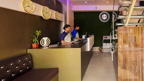 A reception area with multiple clocks, a reception desk, and a seating area. - Hotel Heritage (Cooch Behar)