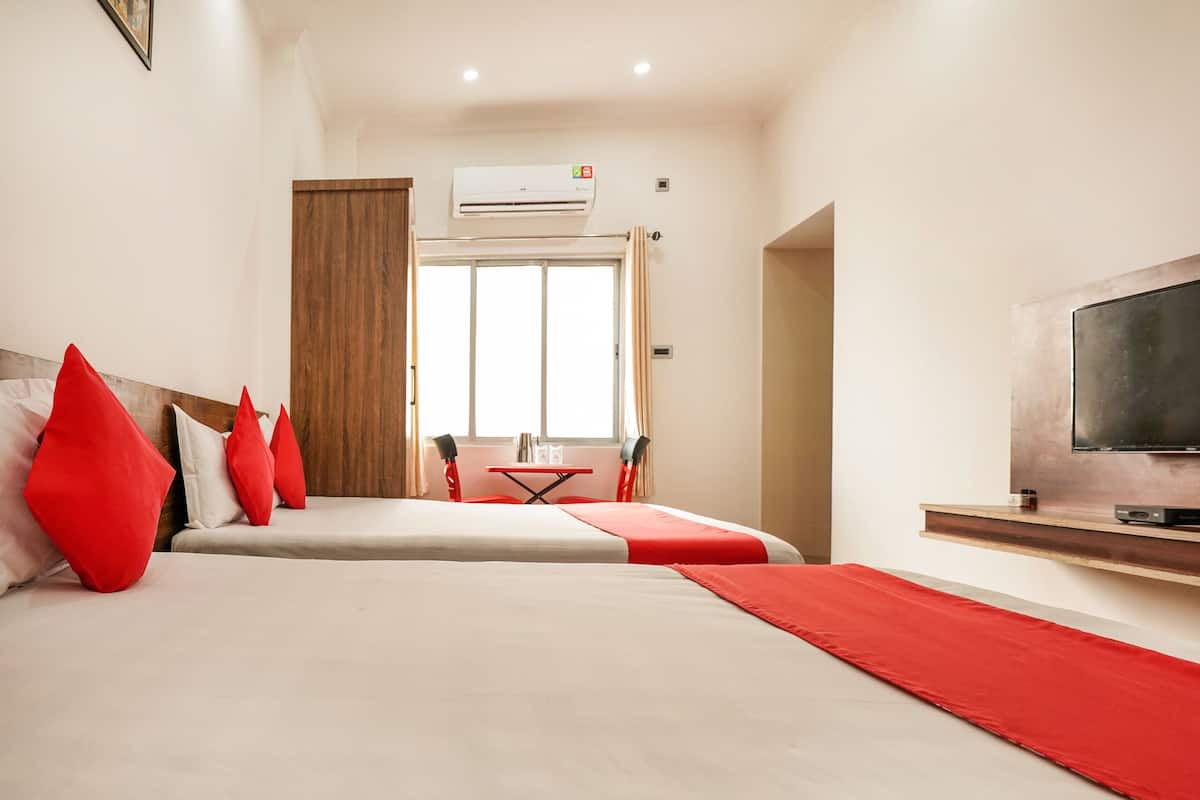 A hotel room with a bed, a TV, a desk, and a window.
