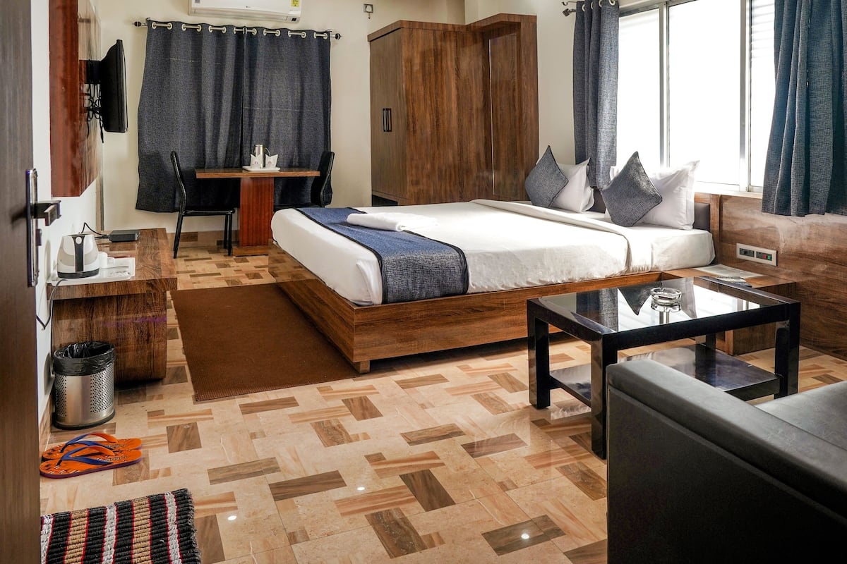 A modern hotel room with a large bed, a desk, a sofa, and a TV.