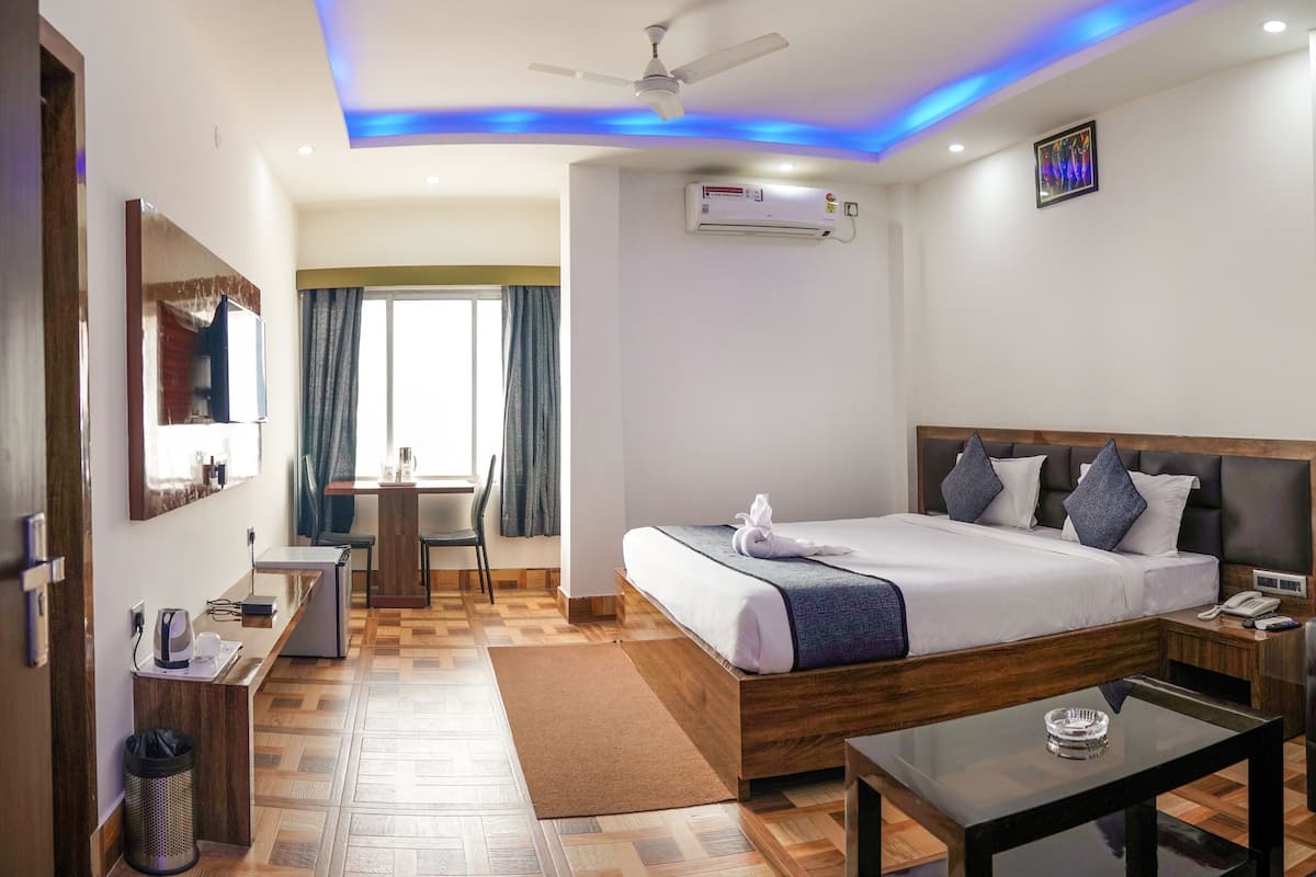 A hotel room with a bed, bedside table, desk, chair, and a view of the outside.