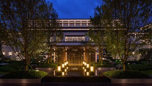 A modern building with a reflective water feature in front, surrounded by trees and well-lit pathways. - Gran Melia Chengdu (Chengdu)