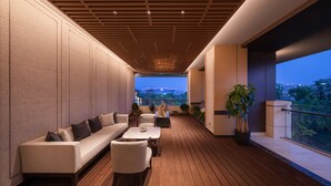 A modern outdoor lounge area with a wooden deck, a sofa, chairs, and a table. - Gran Melia Chengdu (Chengdu)
