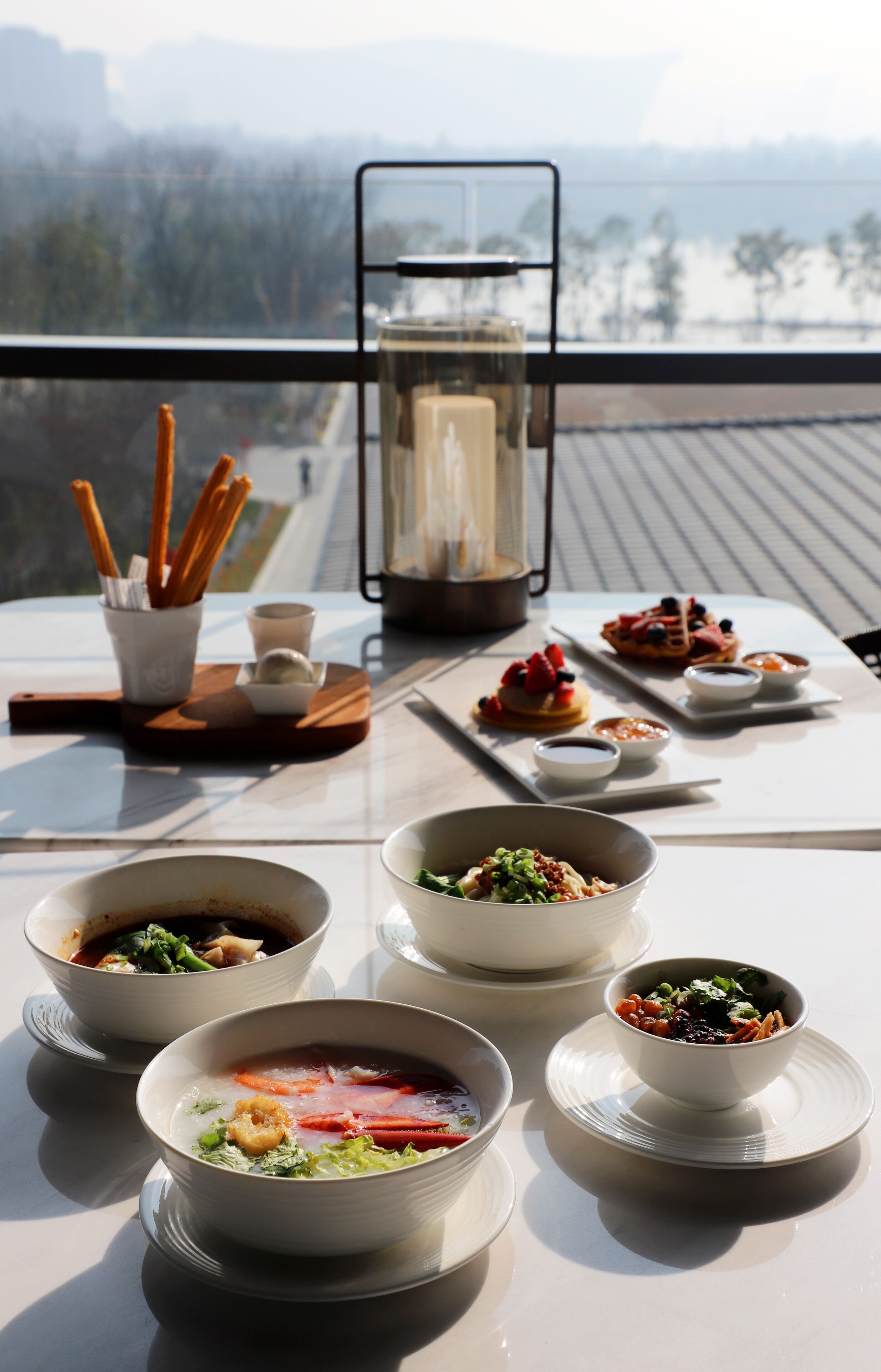 Una mesa de comedor con varios platos, un candelabro y vistas al exterior.