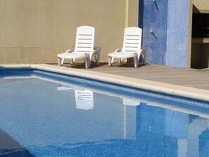 A swimming pool with two white lounge chairs and a tiled wall. - Amina house with private swimming pool not overlooked, free WIFI internet. (L'Escala)