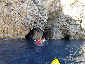 Un groupe de personnes pratiquant le kayak dans un étroit passage d’eau entre de hautes falaises rocheuses.