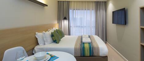 Ein Hotelzimmer mit einem Bett, einem Nachttisch und einem an der Wand befestigten Fernseher.