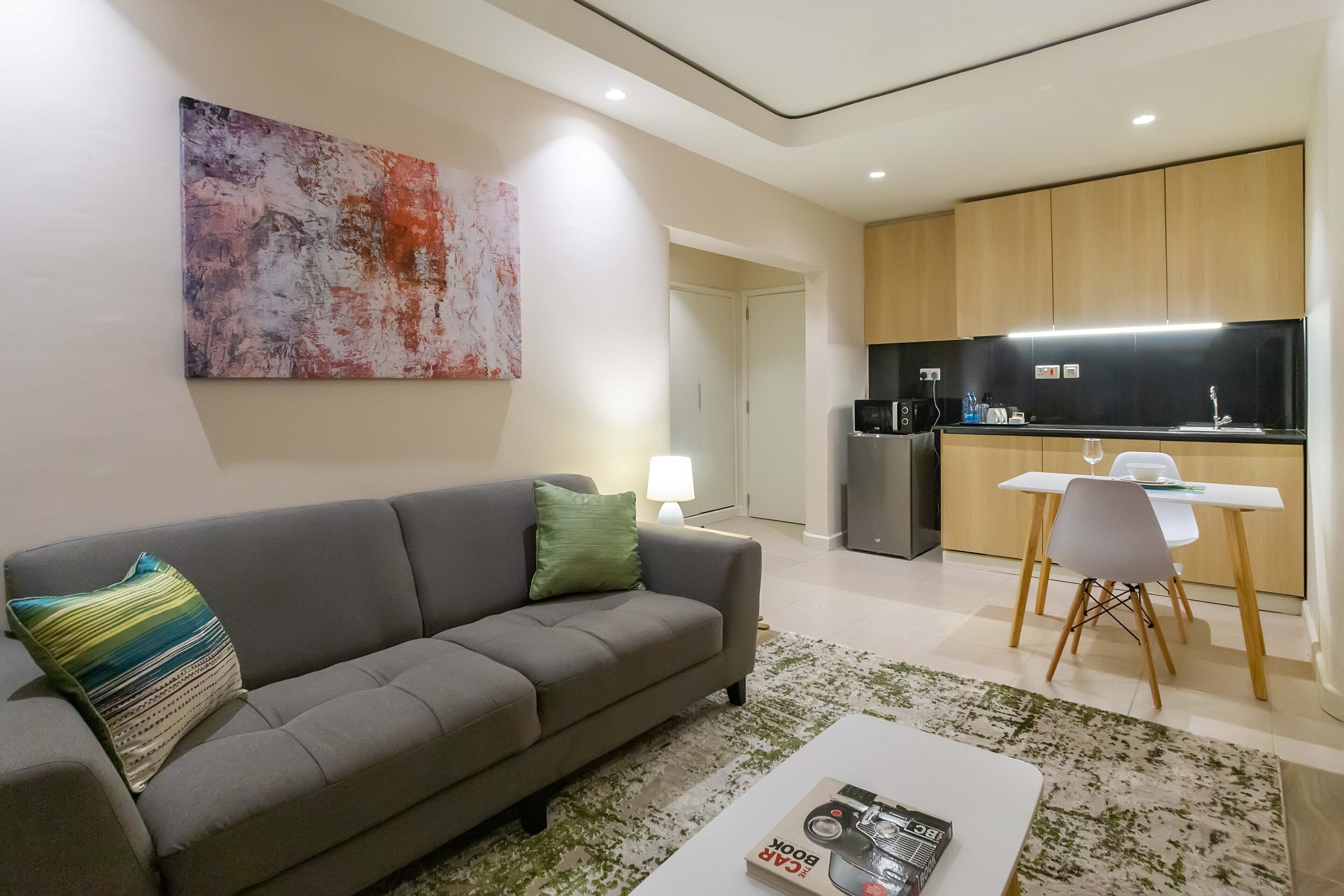 Ein modernes Wohnzimmer mit einem grauen Sofa, einem Couchtisch und einem Bild an der Wand.