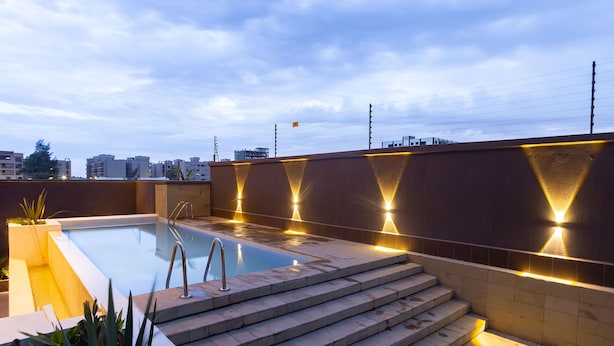 A rooftop swimming pool with steps leading down to the water, surrounded by a low wall with integrated lighting.
