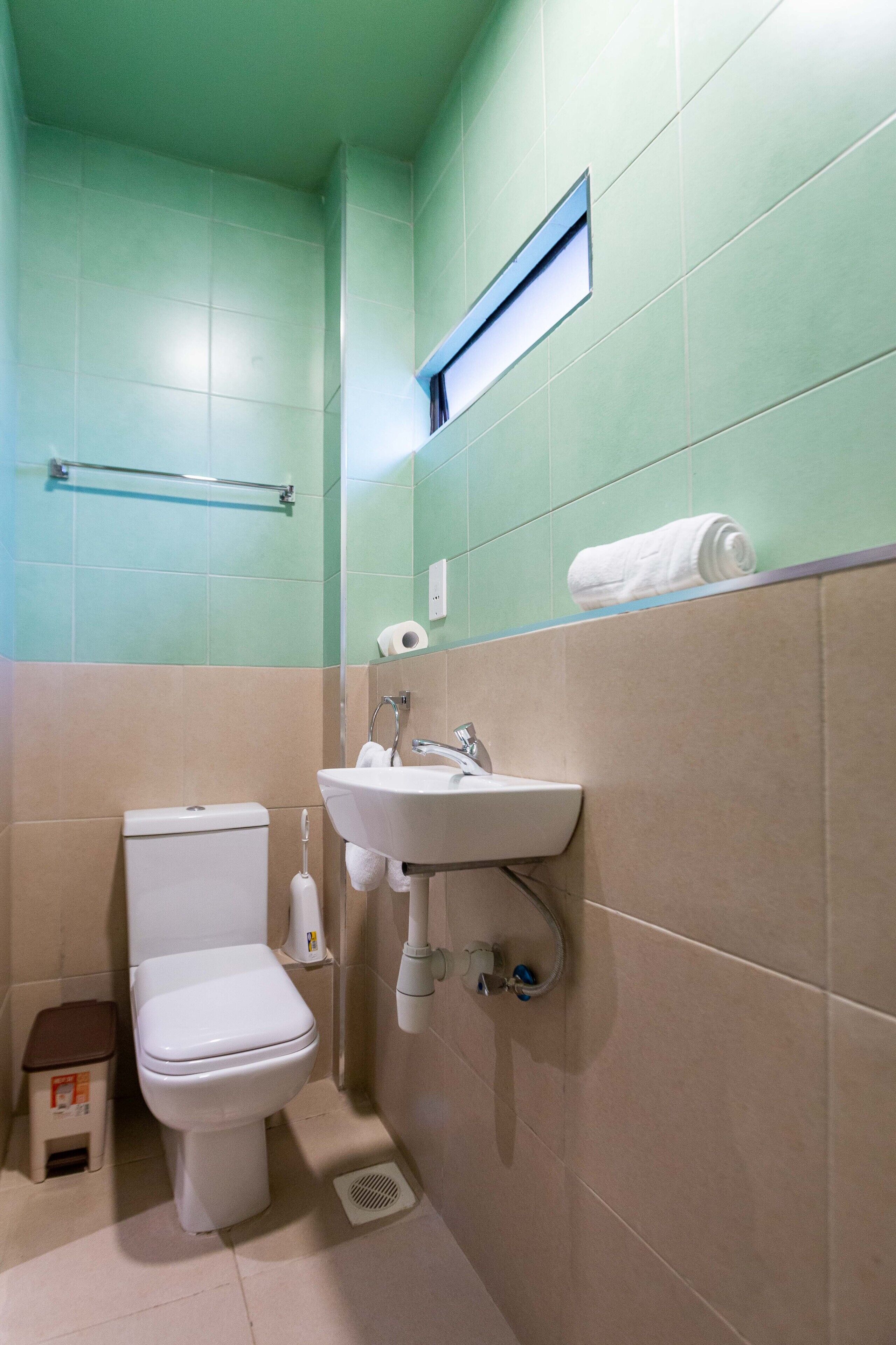 Un baño con inodoro, lavamanos y toallero.