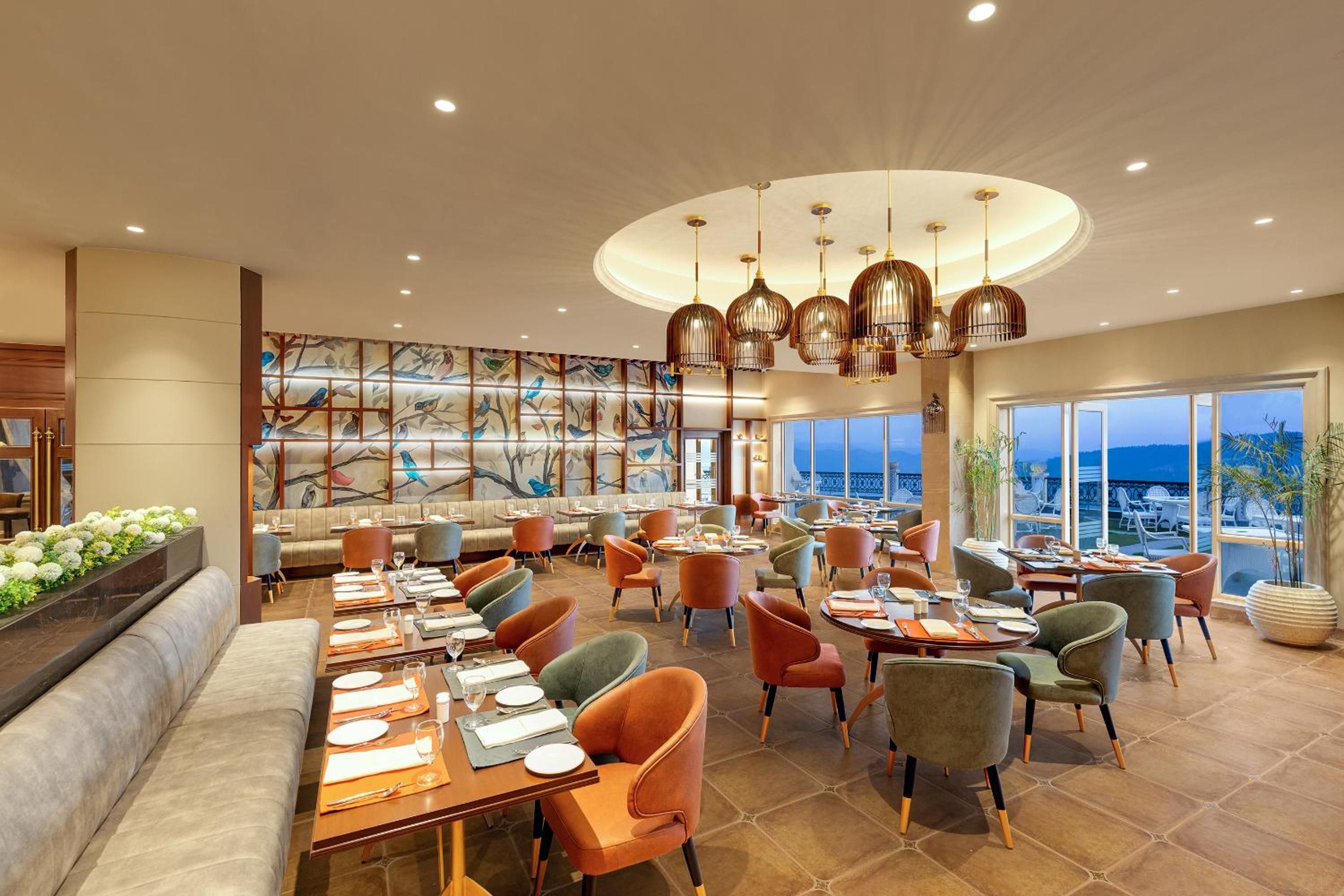 A spacious restaurant with multiple dining areas, a large mural, and a view of the sea.