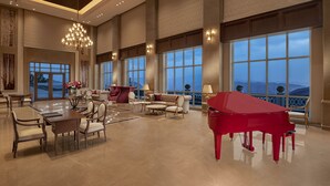 A spacious living room with a grand piano, large windows, and a high ceiling with recessed lighting. - Welcomhotel by ITC Hotels, Tavleen, Chail (Shimla)