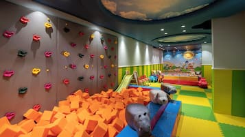 A children's play area with climbing walls, a slide, and foam pit.