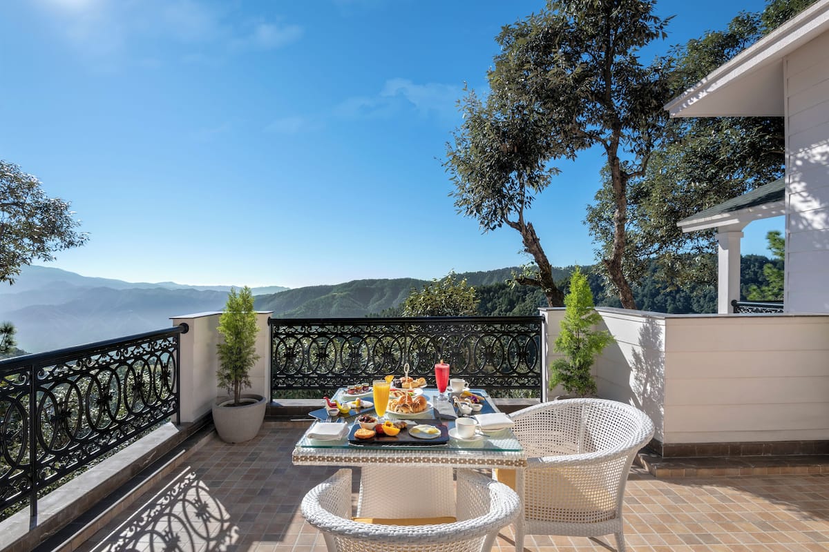 A terrace with a table set for breakfast, overlooking a mountainous landscape.