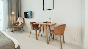 A modern hotel room with a bed, a desk with two chairs, a TV, and a framed inspirational quote on the wall. - Time Apartments Ylistönmäki (Jyväskylä)