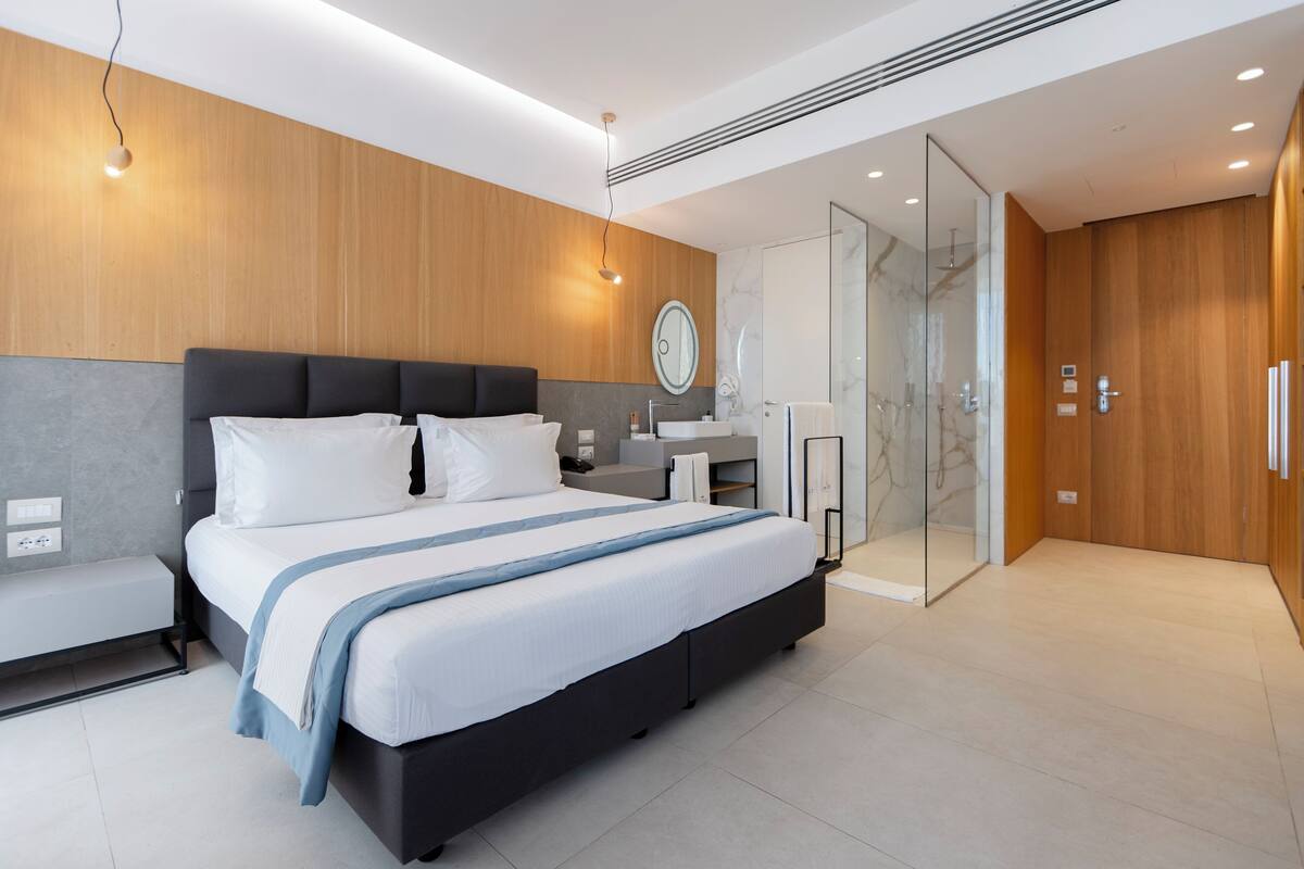 Un dormitorio moderno con una cama grande, mesitas de noche, un tocador con espejo y un vestidor.