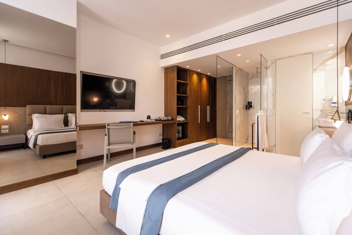 Una habitación de hotel moderna con una cama grande, un escritorio, un armario y un baño.