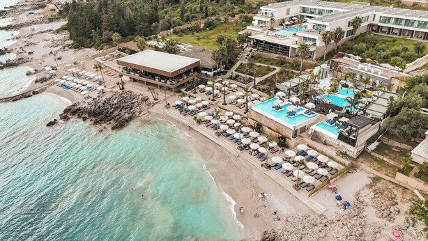 An aerial view of a coastal resort with a beach, a pool area, and a restaurant named "SANUR". - Empire Beach Resort ADULTS ONLY (Himarë)