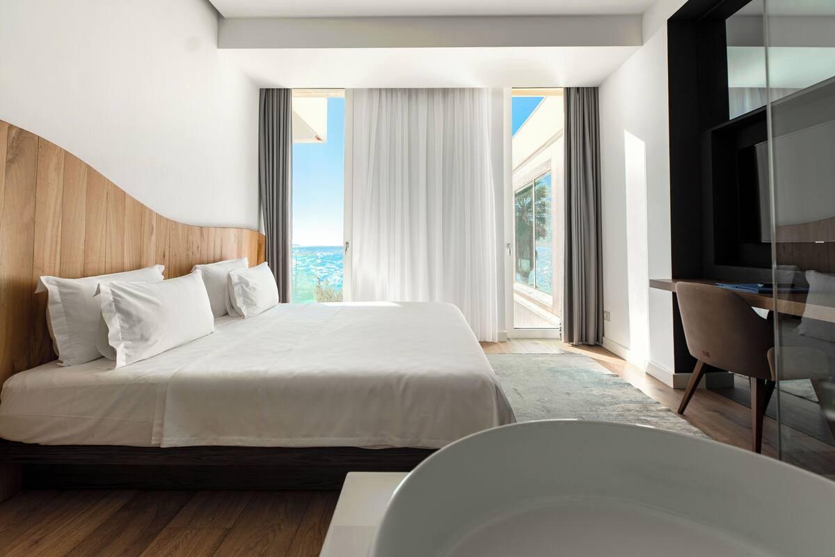 Una habitación de hotel moderna con una cama grande, un escritorio y vistas al océano.