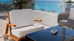 A balcony with two white cushioned chairs, a small table, and a potted plant. - Empire Beach Resort ADULTS ONLY (Himarë)