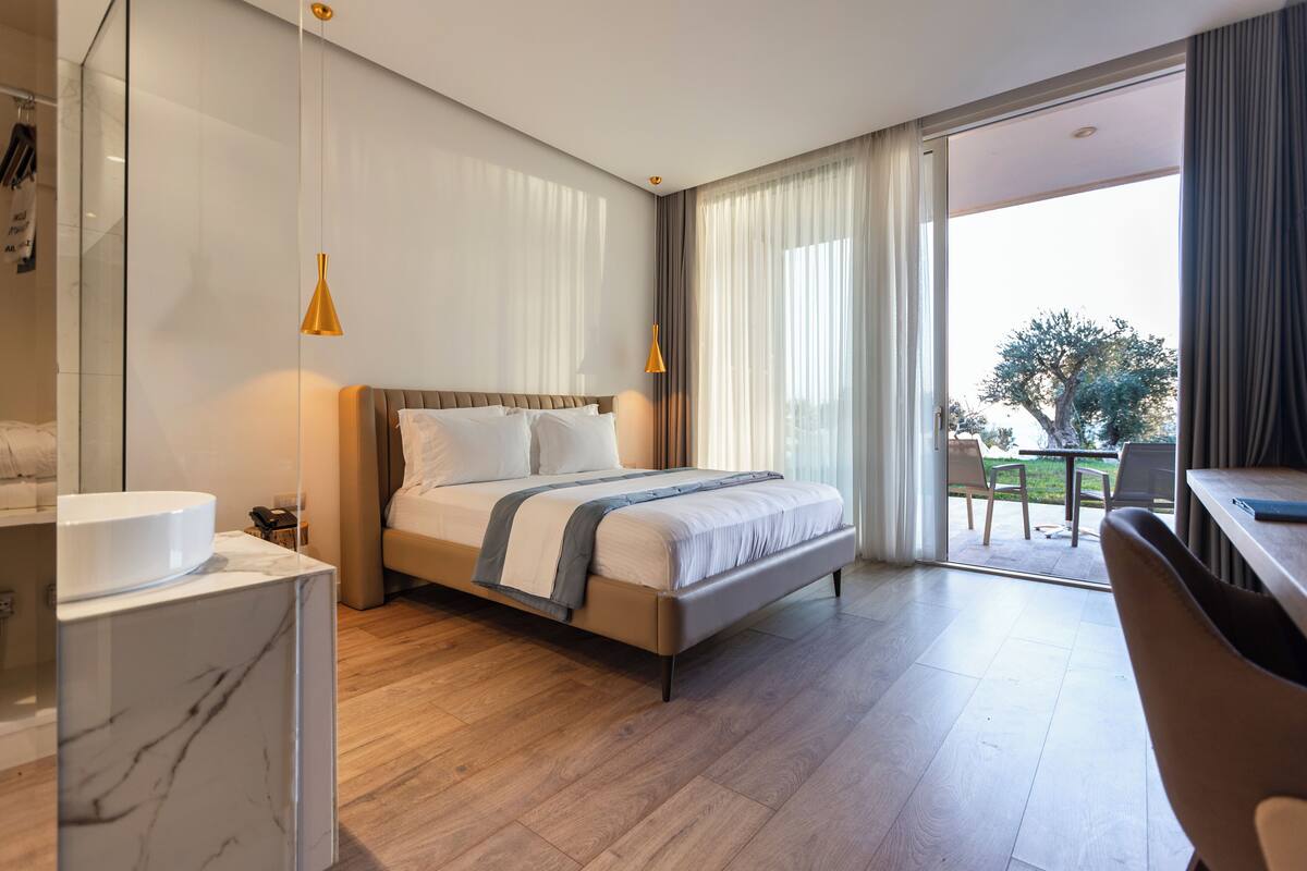 Una habitación de hotel moderna con una cama grande, un escritorio y vistas al exterior.