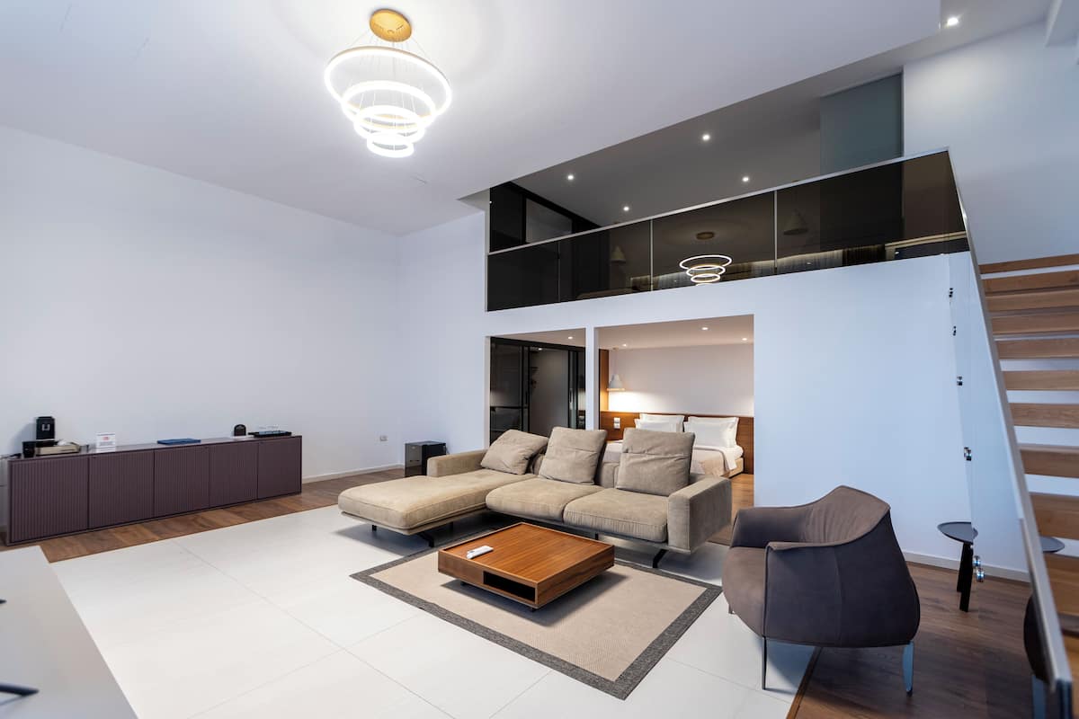 Una sala de estar moderna con un sofá modular, una mesa de centro y una escalera que sube a un nivel superior.