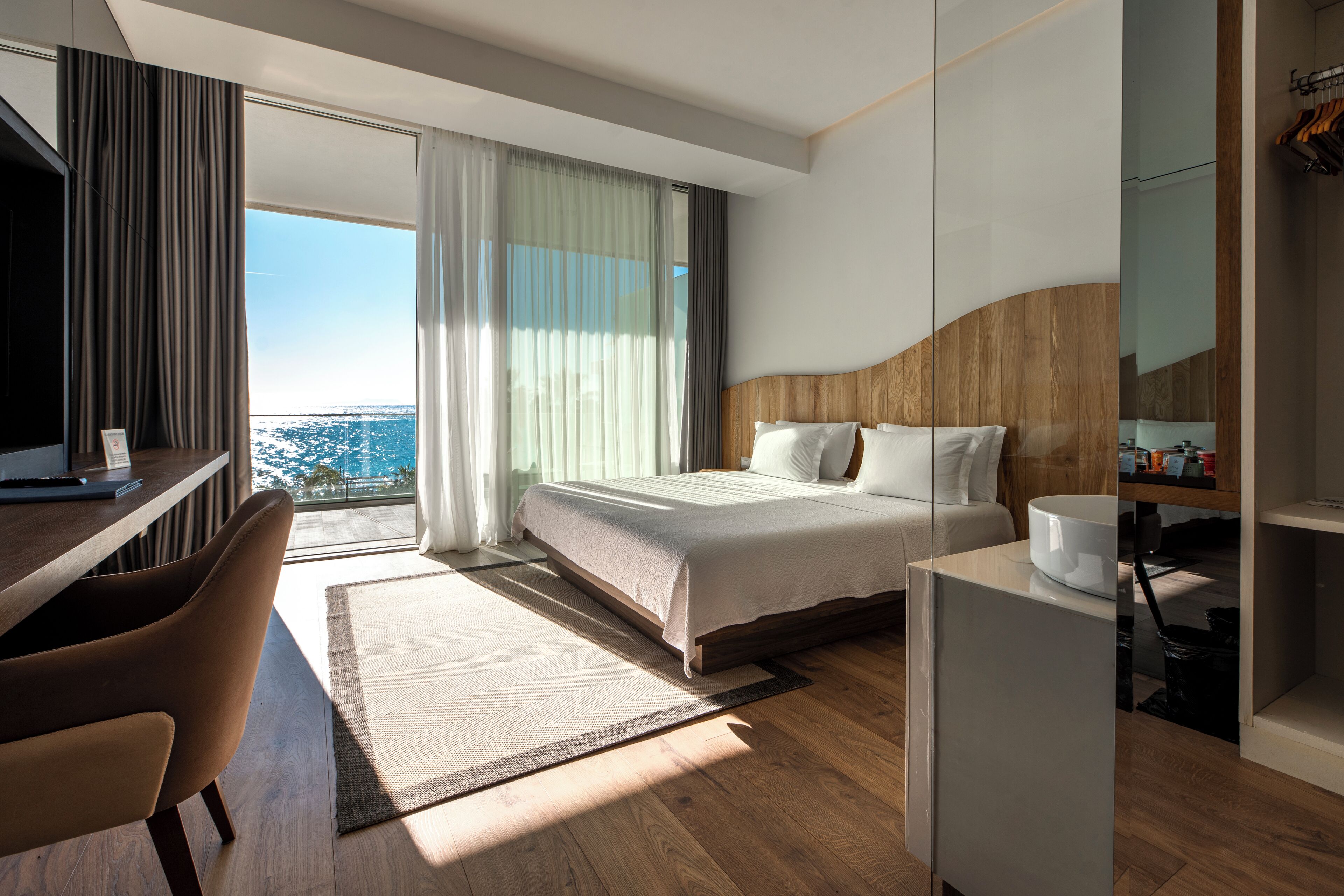 Ein modernes Hotelzimmer mit einem großen Bett, einem Schreibtisch und Blick auf die Stadt.