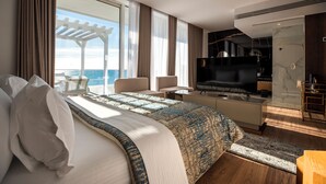 A modern hotel room with a large bed, a TV, a desk, and a view of the ocean. - Empire Beach Resort ADULTS ONLY (Himarë)