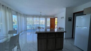 Una cocina moderna con una isla central, un refrigerador y un comedor con mesa y sillas.