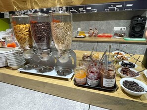 A buffet setup with various food items and condiments. - Ibis Budget Cognac (Chateaubernard)