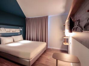 Una habitación de hotel moderna con una cama grande, un escritorio y un espejo.