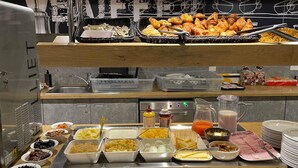 A buffet with various food items and a coffee station. - Ibis Budget Cognac (Chateaubernard)